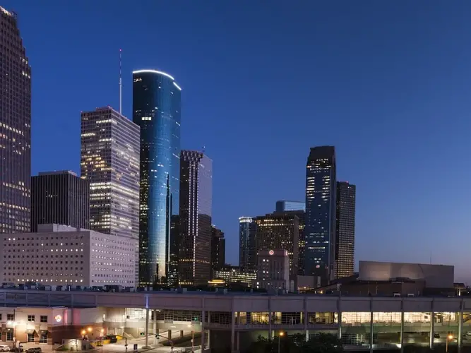 A city skyline at dusk with several skyscrapers and a blue sky