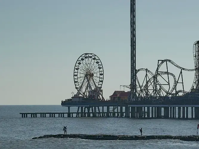 a pier with a Ferris wheel and roller coaster on it
