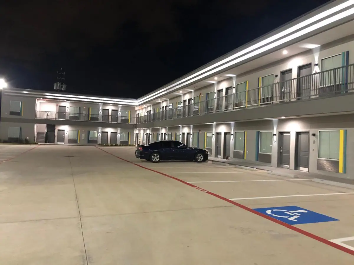 A two-story building with balconies and a parking lot at night.